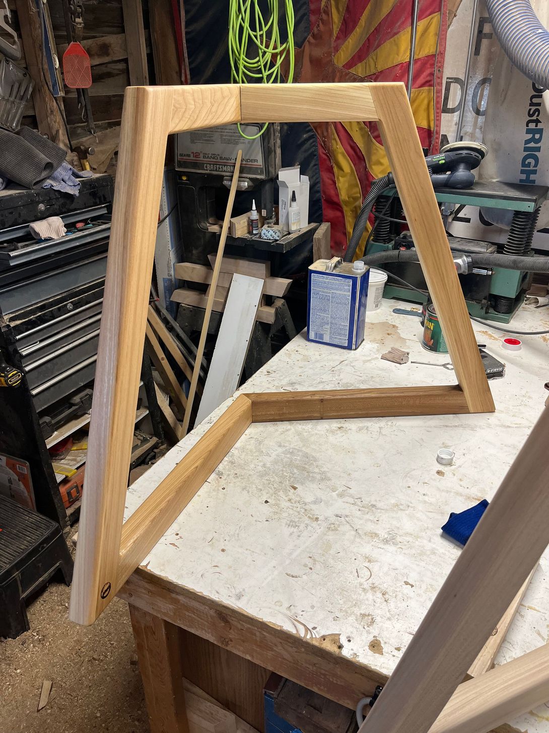 Wooden A-frame, partially constructed on a workbench in a workshop.