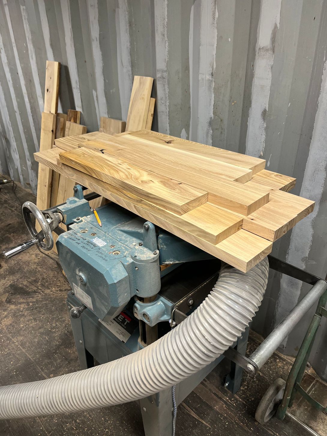 Planer with wood stacked on top; a workshop setting.