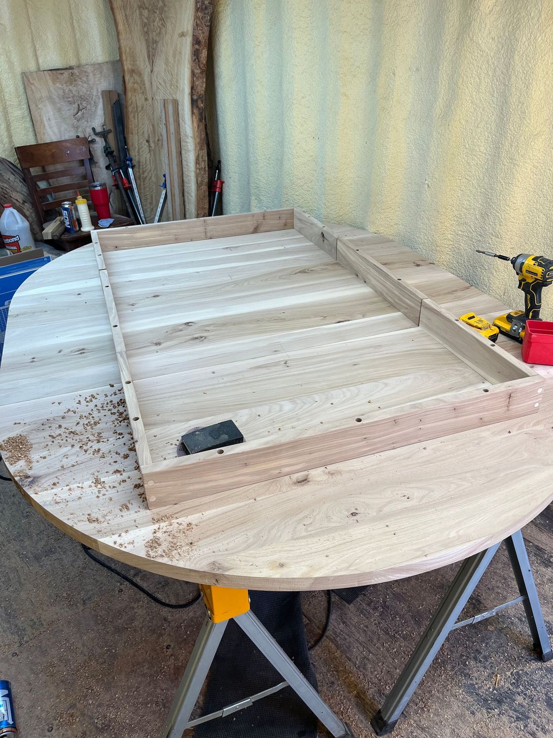 Wood table being assembled on a larger round table; woodworking in workshop.