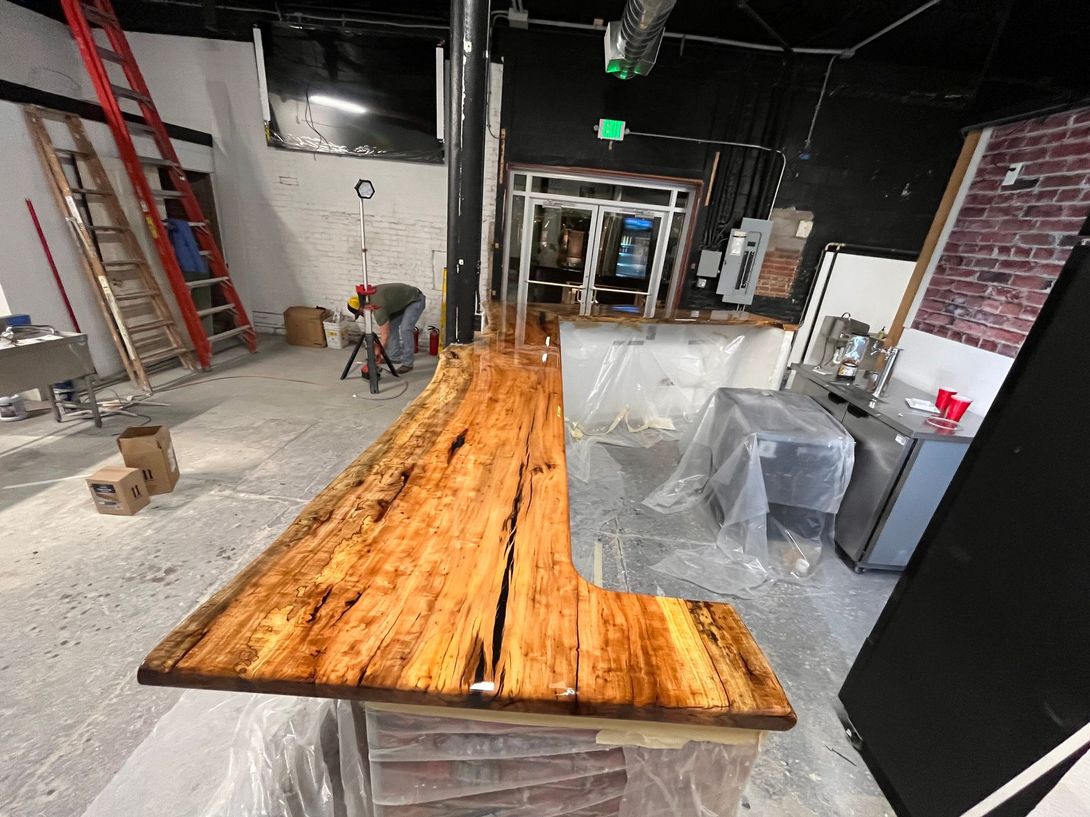 A live edge wooden bar, under construction in a commercial space.