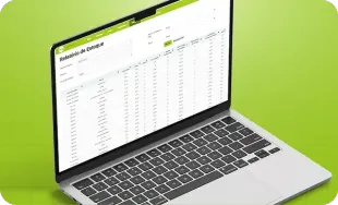 Laptop prateado exibindo uma planilha sobre um fundo verde brilhante.