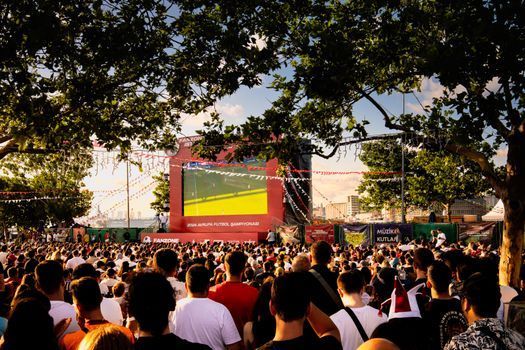 Lounge de hotel brasileiro com telão de futebol e hóspedes em clima de Copa do Mundo