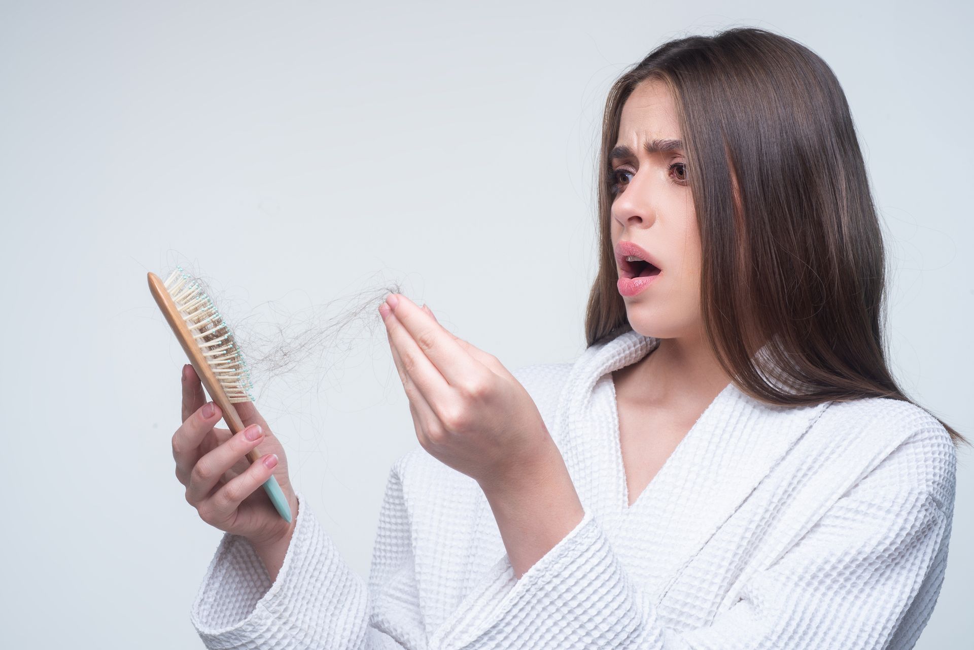 a woman is holding a brush and looking at her hair .