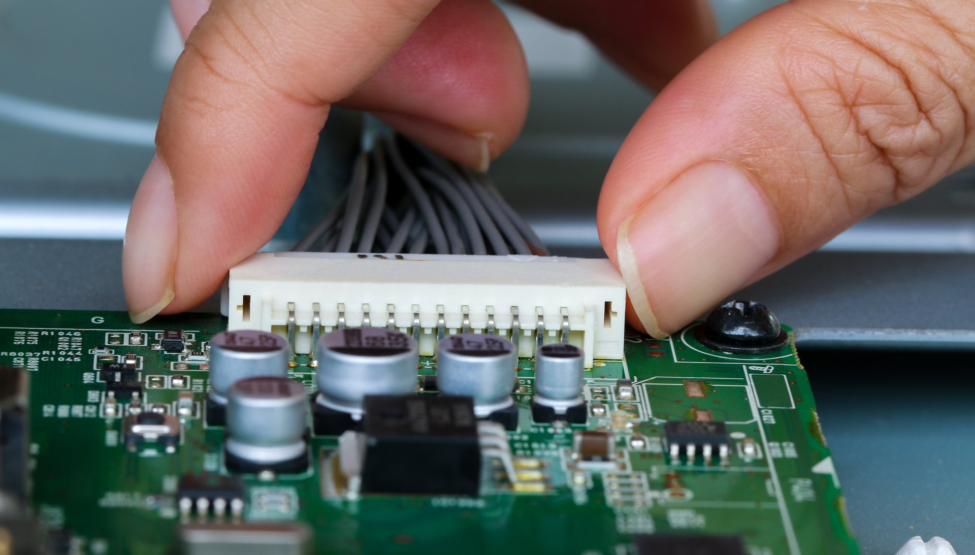 man installing a cable connector to electronic prototype PCB