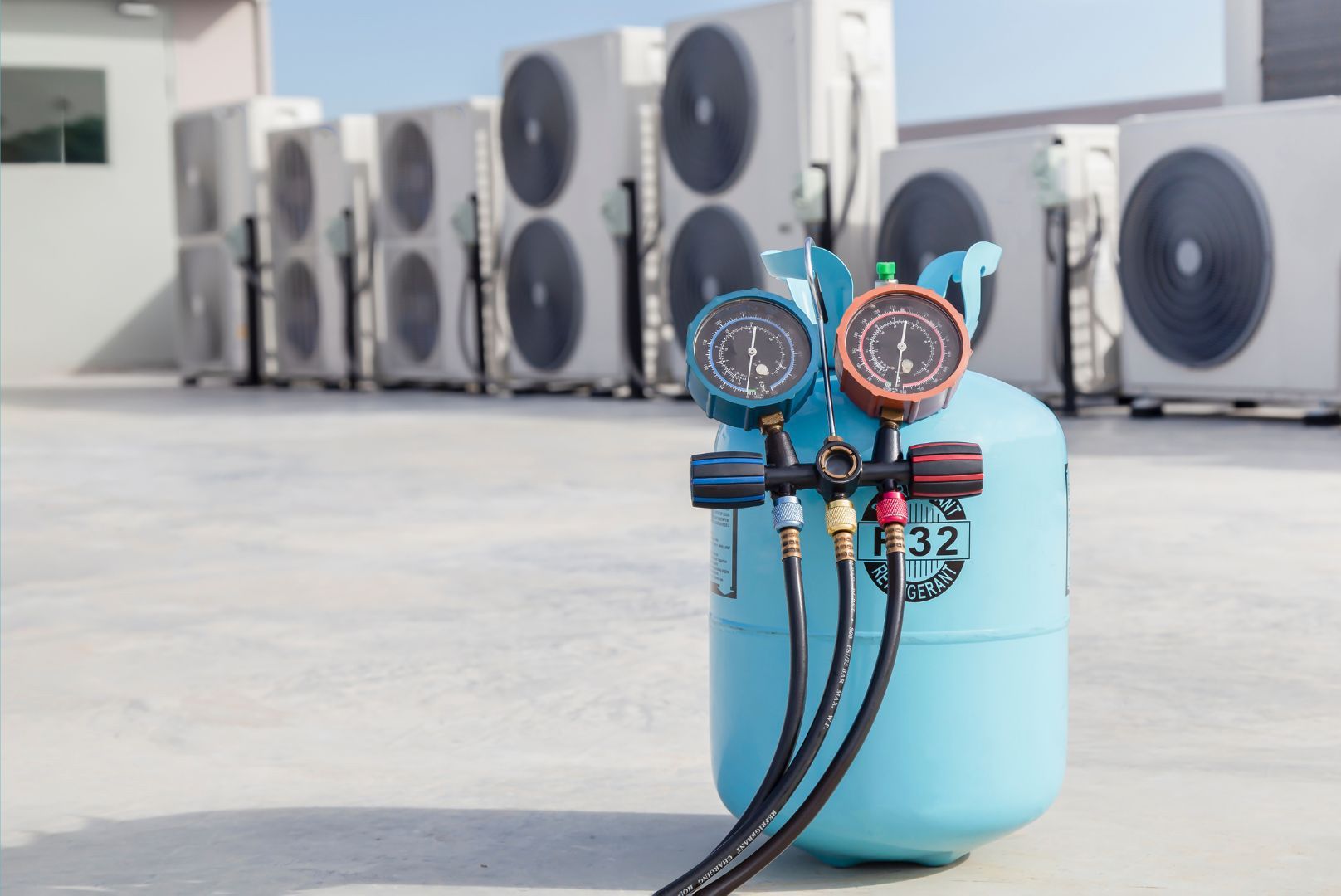 A cylinder of refrigerant is sitting in front of a row of air conditioners.