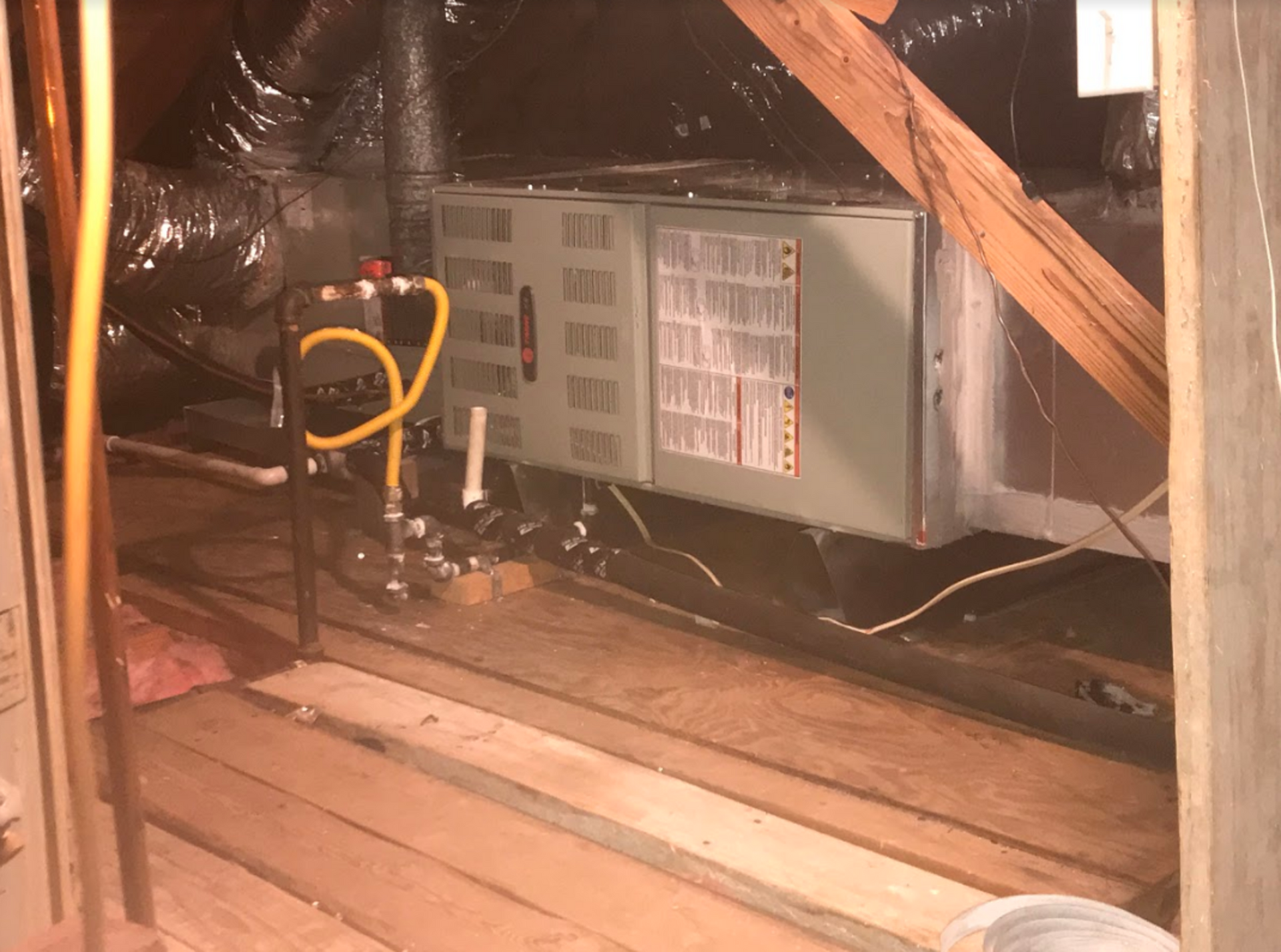 An air conditioner is sitting in the attic of a house.