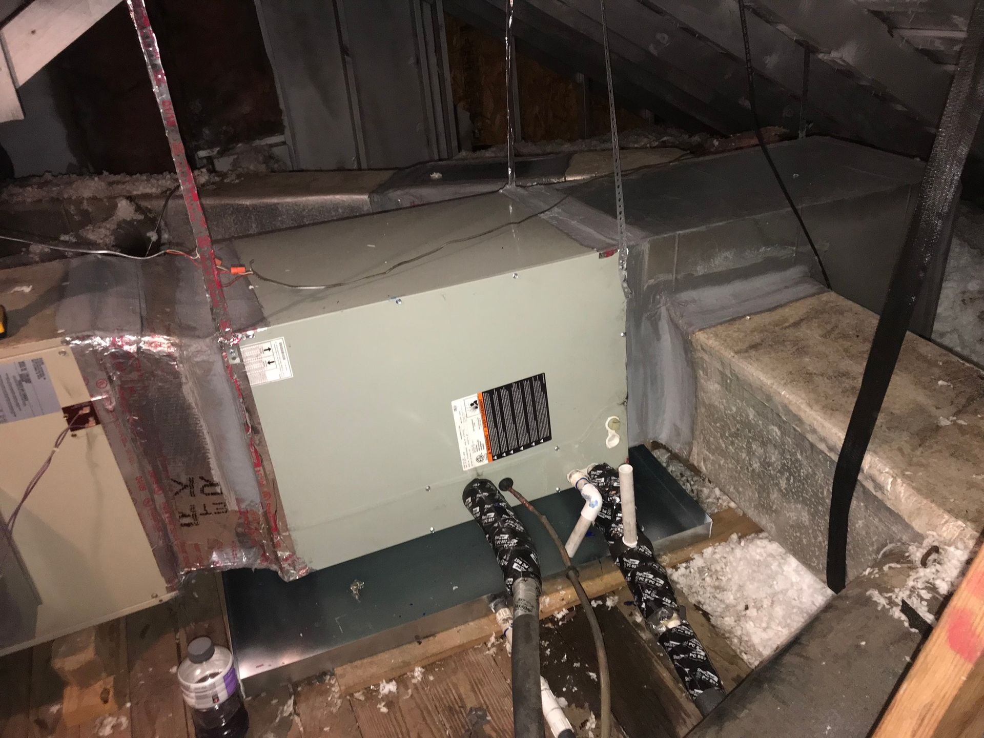 An air conditioner is sitting in the attic of a house.