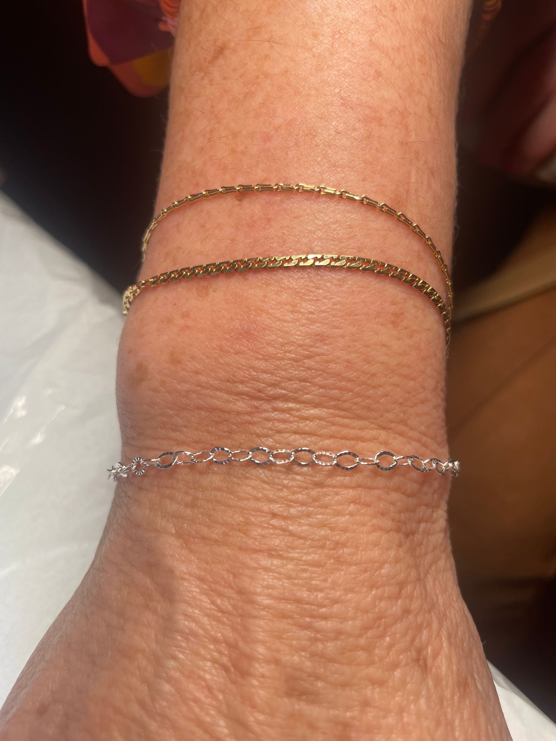 A woman is wearing three different bracelets on her wrist