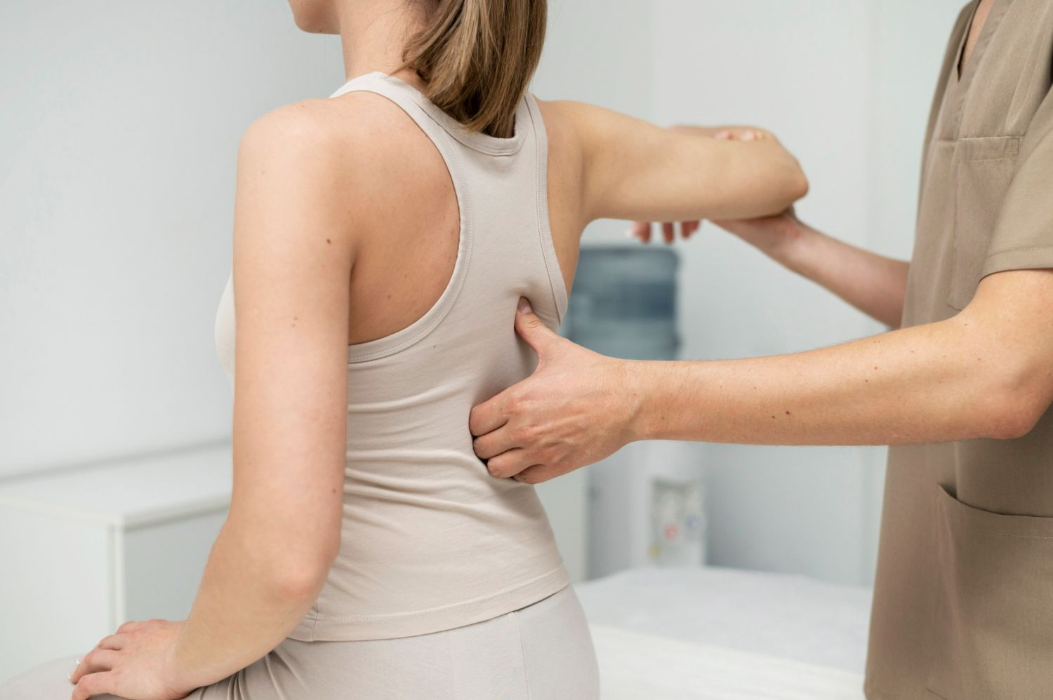 Chiropractor examining a woman's back in a medical office.