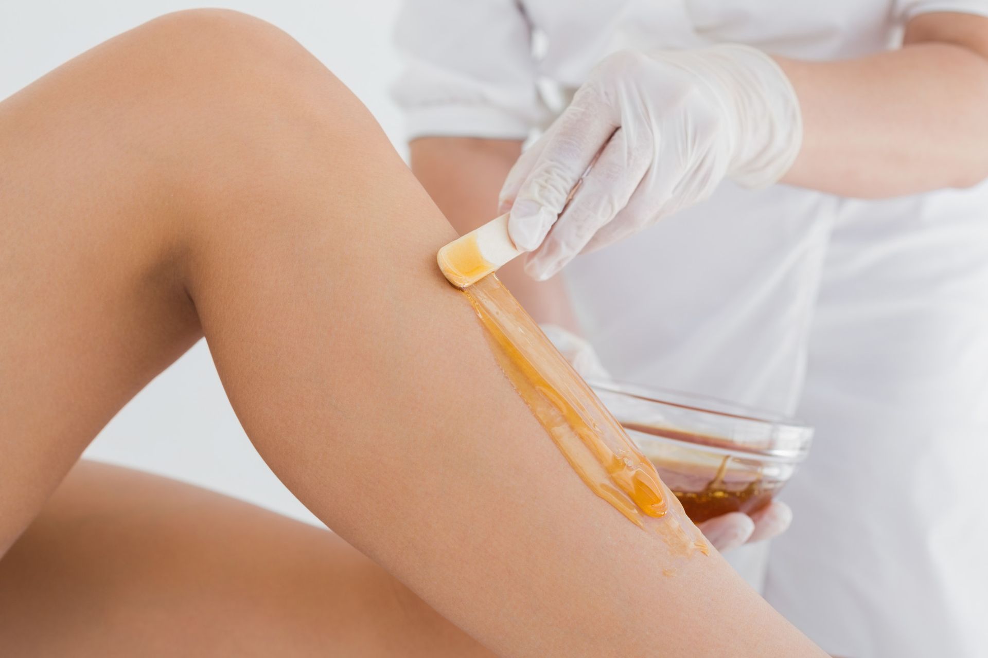 A woman is getting her legs waxed by a doctor.