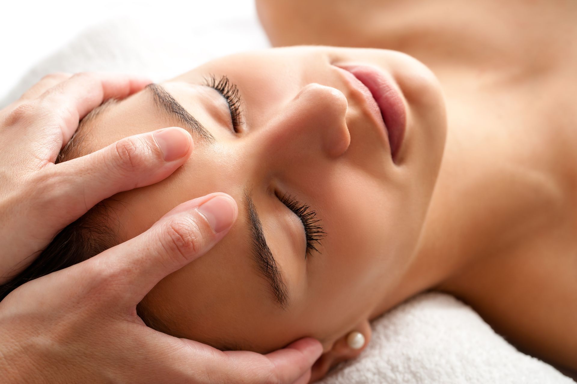 A woman is getting a head massage with her eyes closed.