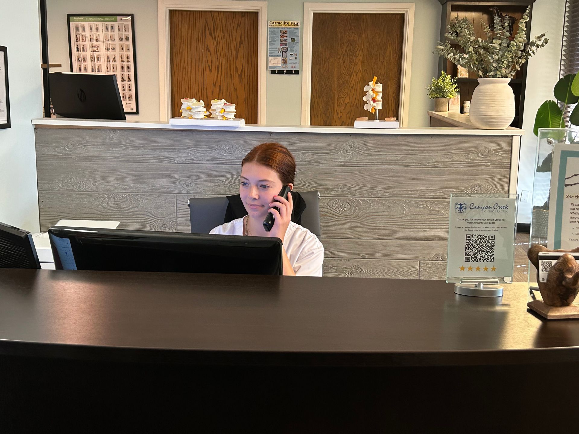 a woman is sitting at a desk talking on a cell phone