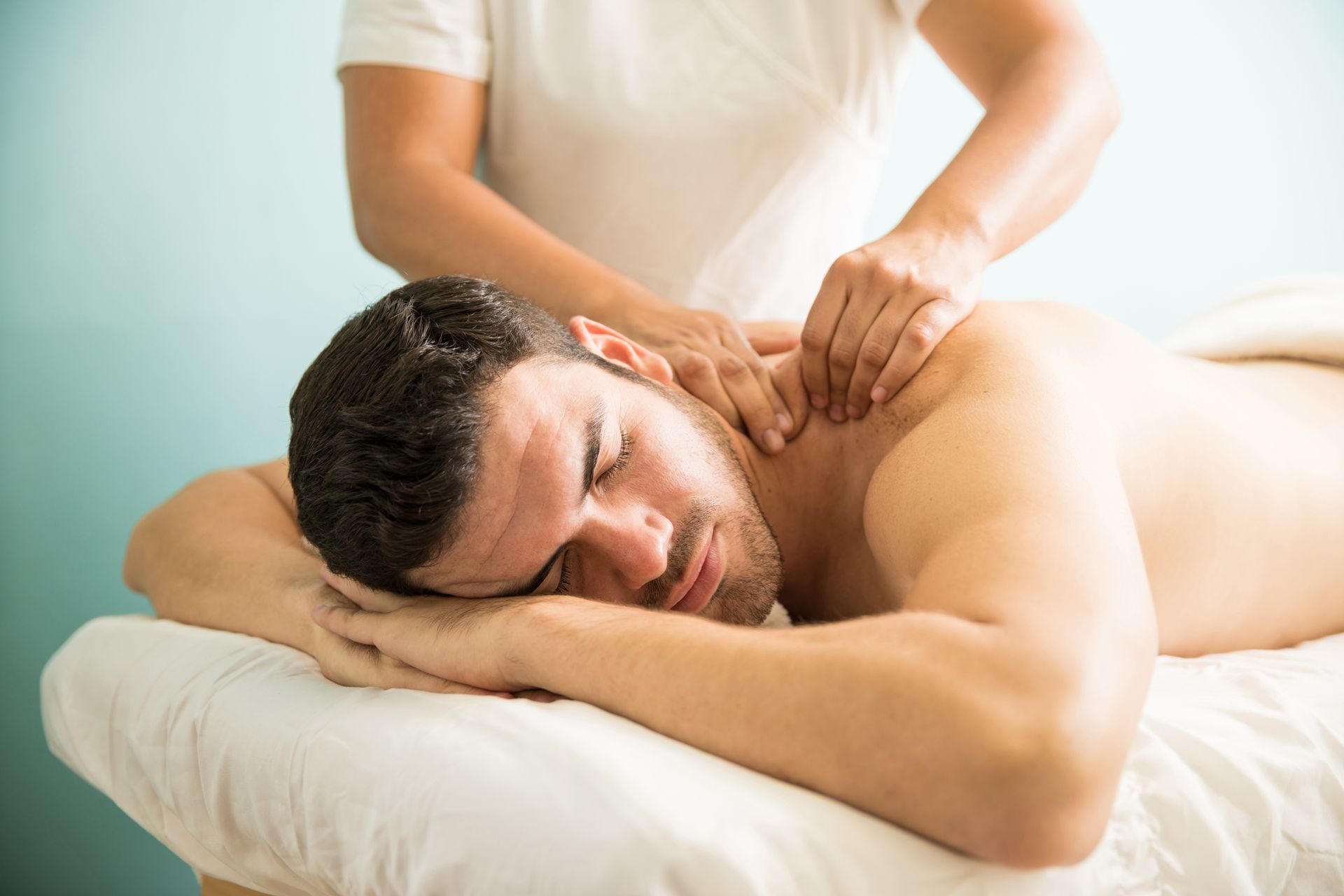A man is laying on a massage table getting a massage from a woman.
