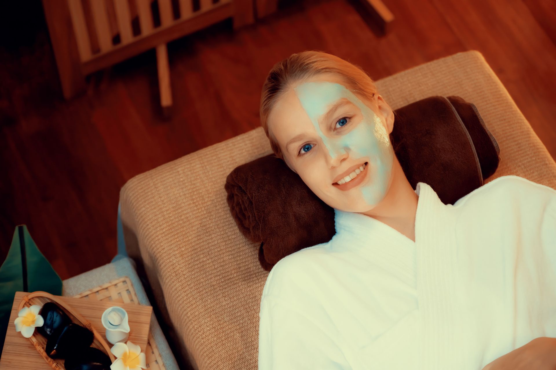 A woman is laying on a couch with a blue mask on her face.