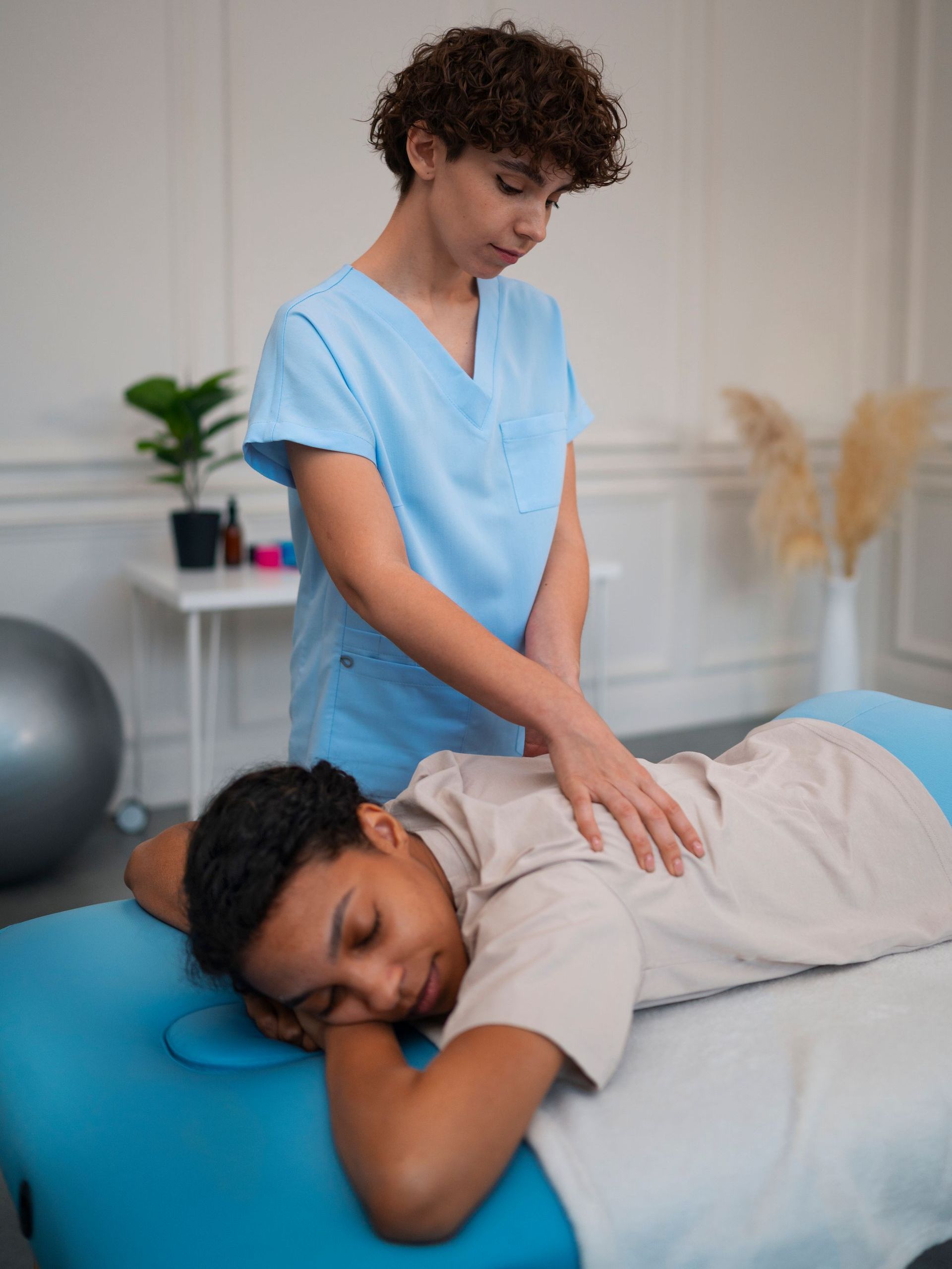 a woman is laying on a table getting a massage from a nurse .