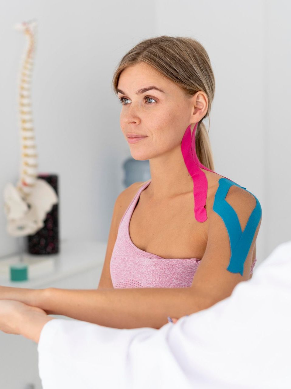 a woman with kinesio tape on her shoulder is sitting in front of a doctor .