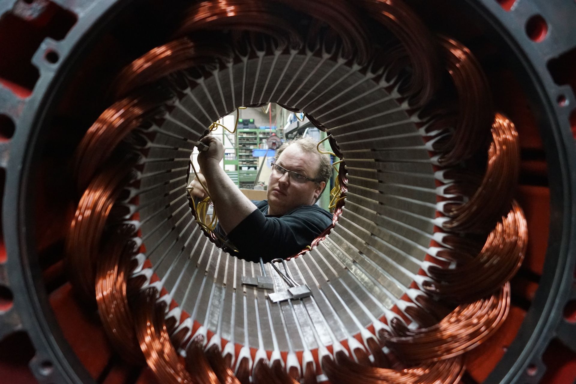 Ein Mann arbeitet an einer großen Maschine mit Kupferdrähten.