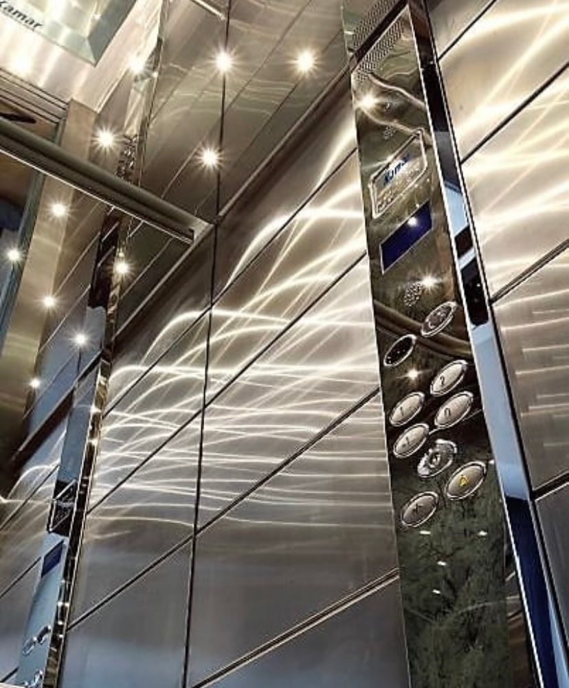 Una stanza vuota con un ascensore e due poster bianchi sul muro.