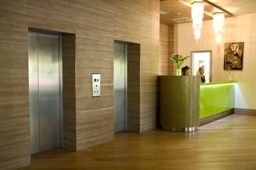Una hall con due ascensori e un bancone verde