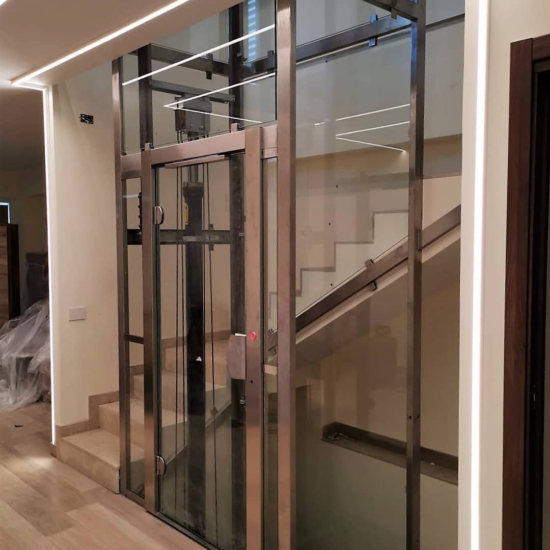 Una stanza vuota con un ascensore e due poster bianchi sul muro.