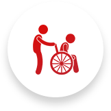 Person assisting a person in a wheelchair, both red icons on a white background.