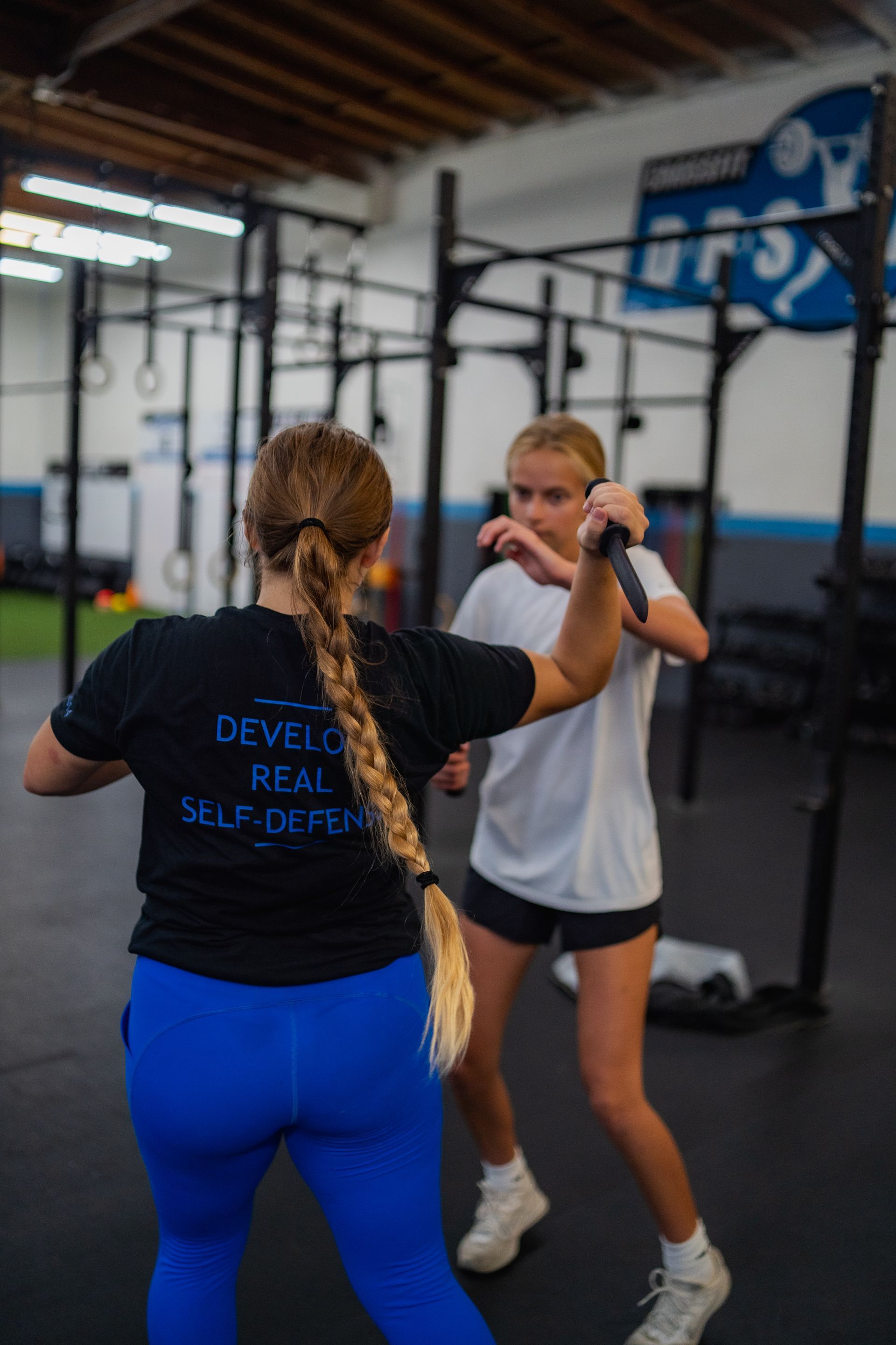 Two women are standing next to each other in a gym.