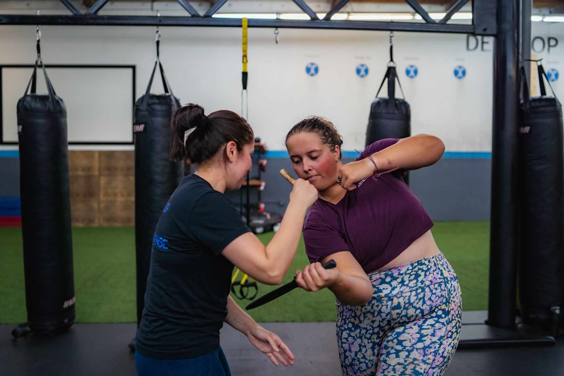 Two women are practicing self defense in a gym.