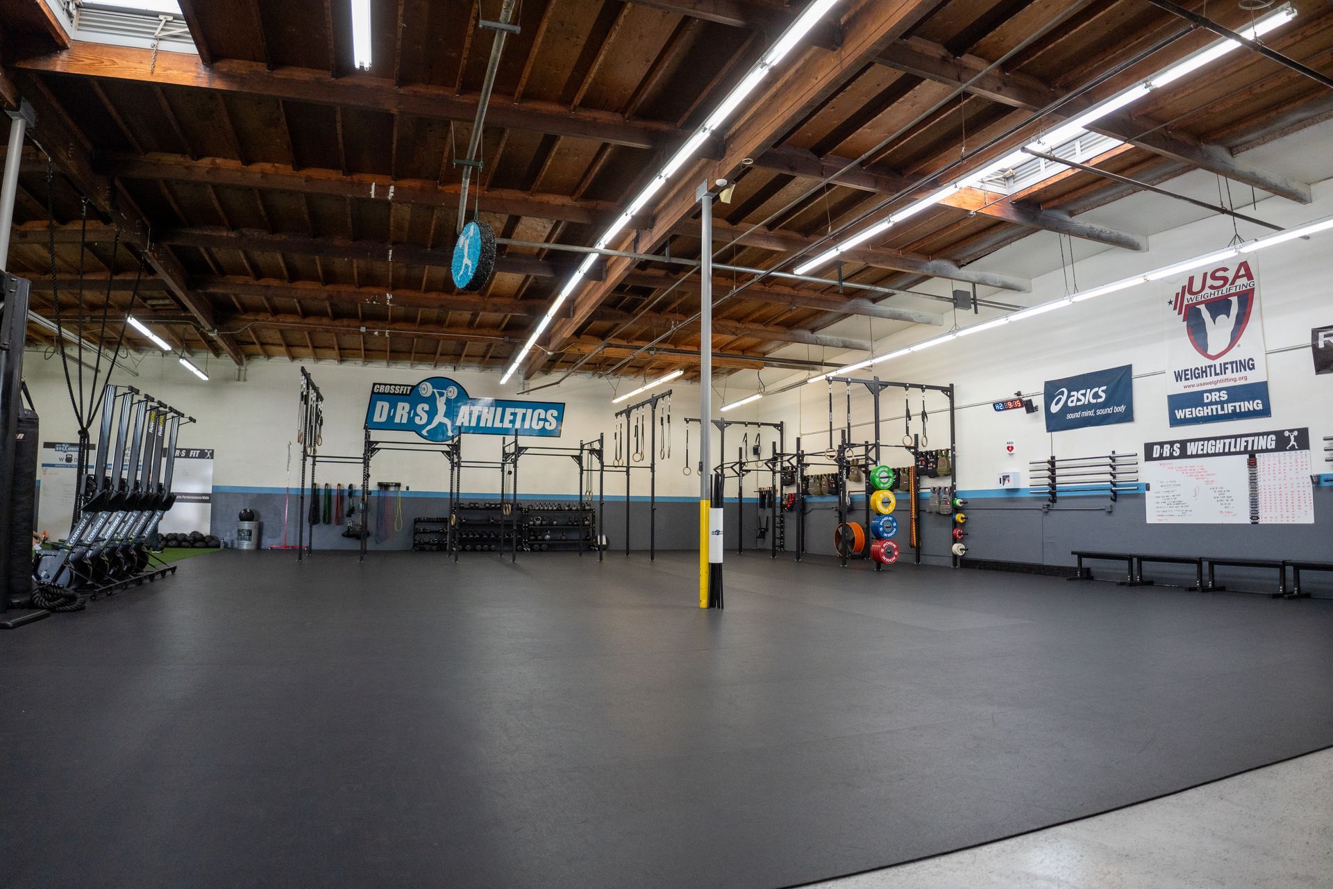 A large empty gym with a black mat on the floor.