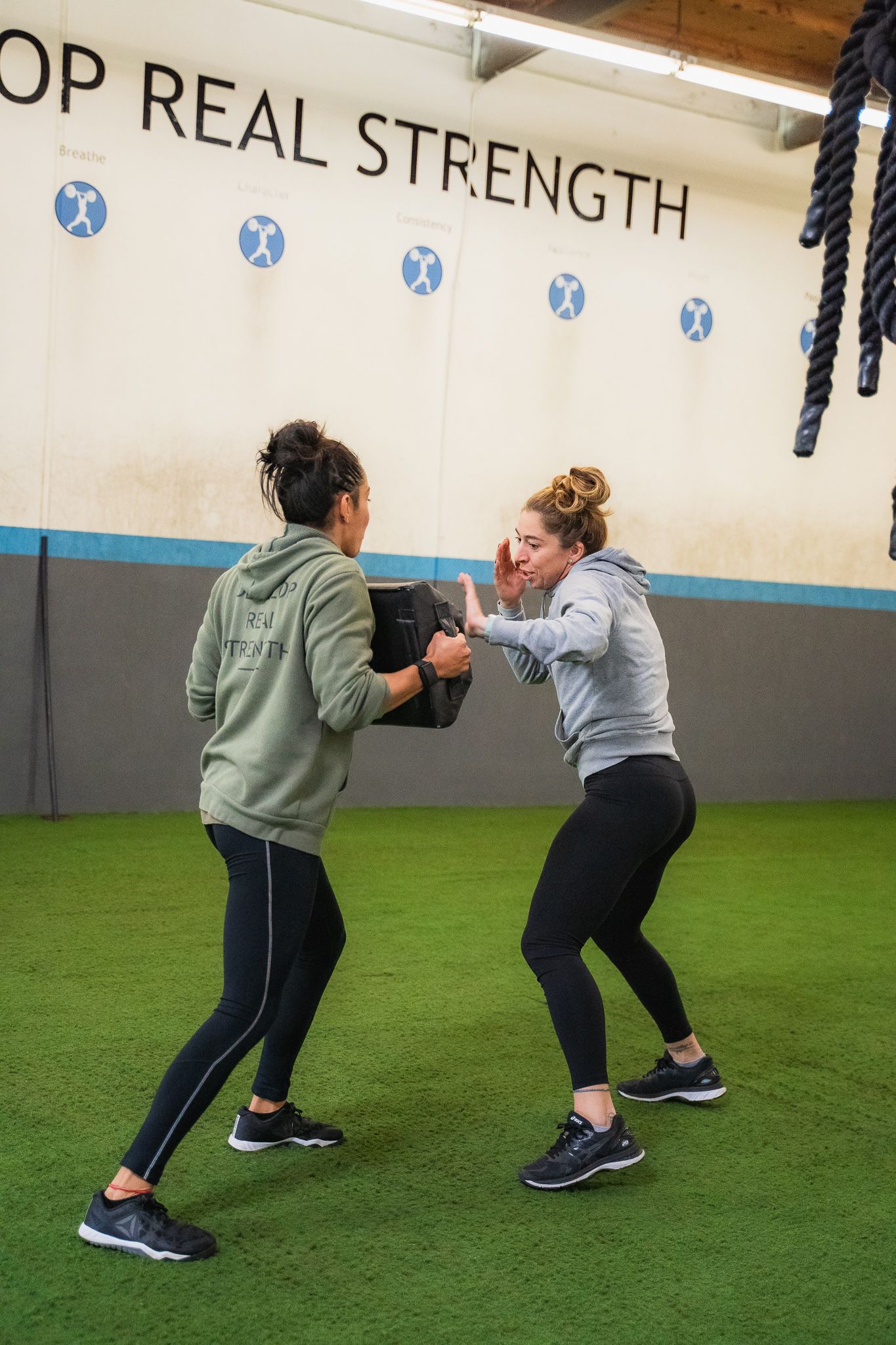 Two women are standing next to each other in a gym.