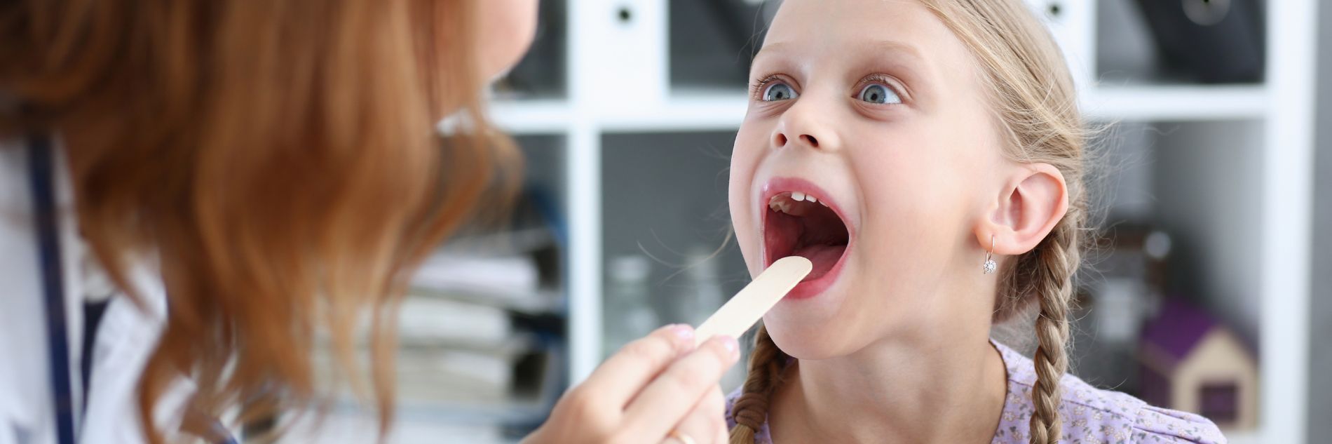 A little girl having her throat examined