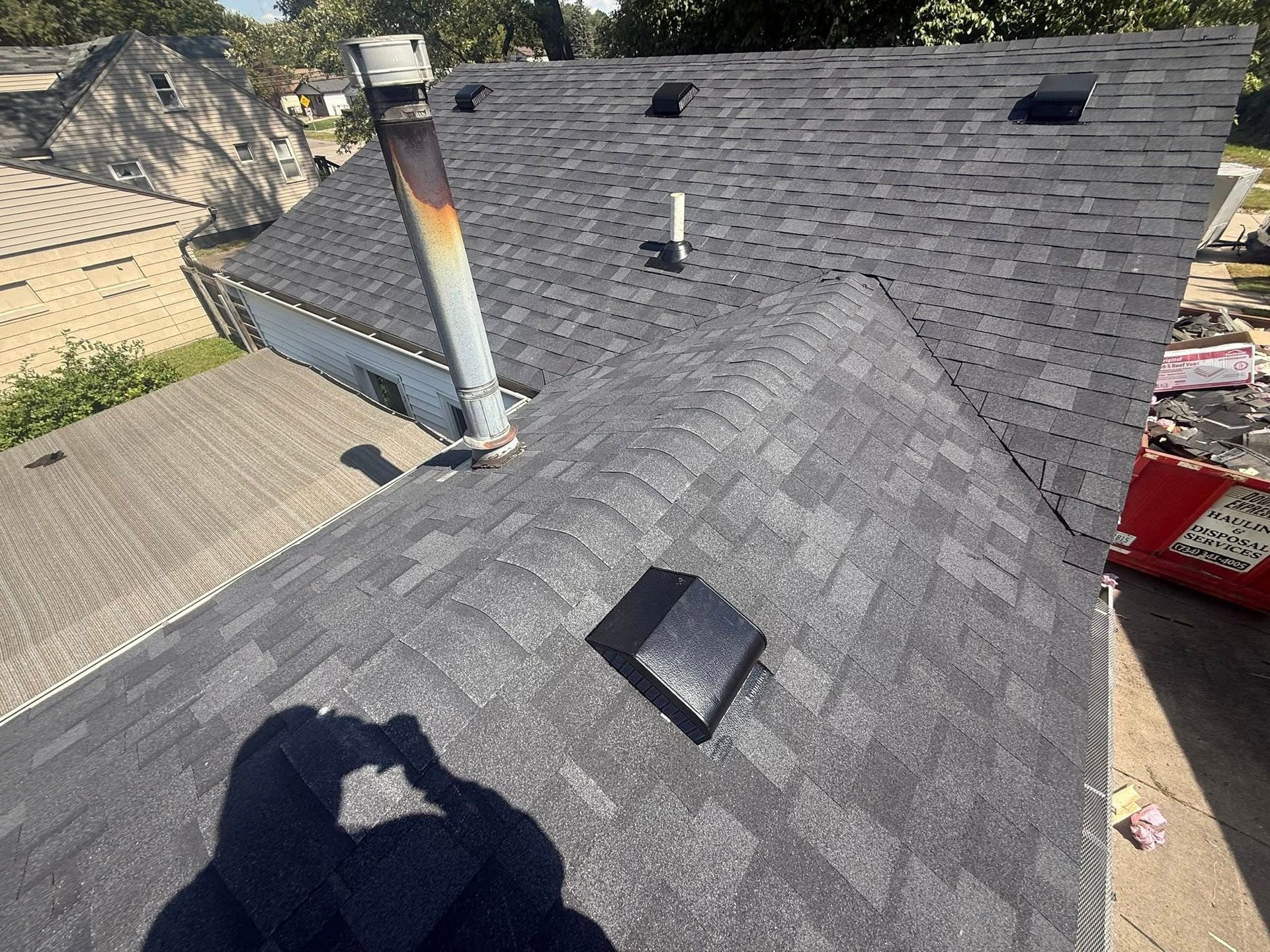 Gray asphalt shingle roof with vents and a chimney.