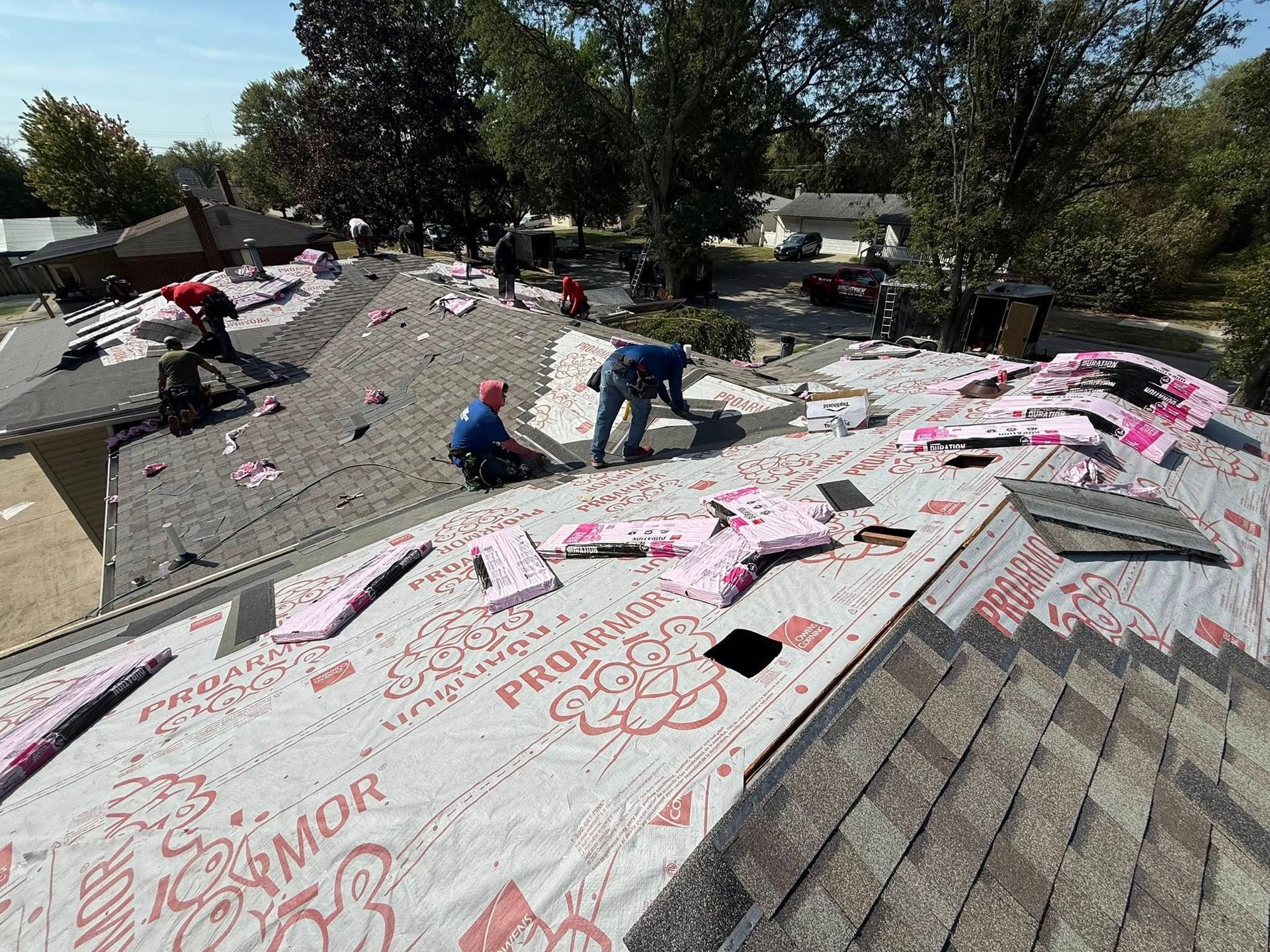 Roofers working on a residential roof, installing insulation. Overcast day.
