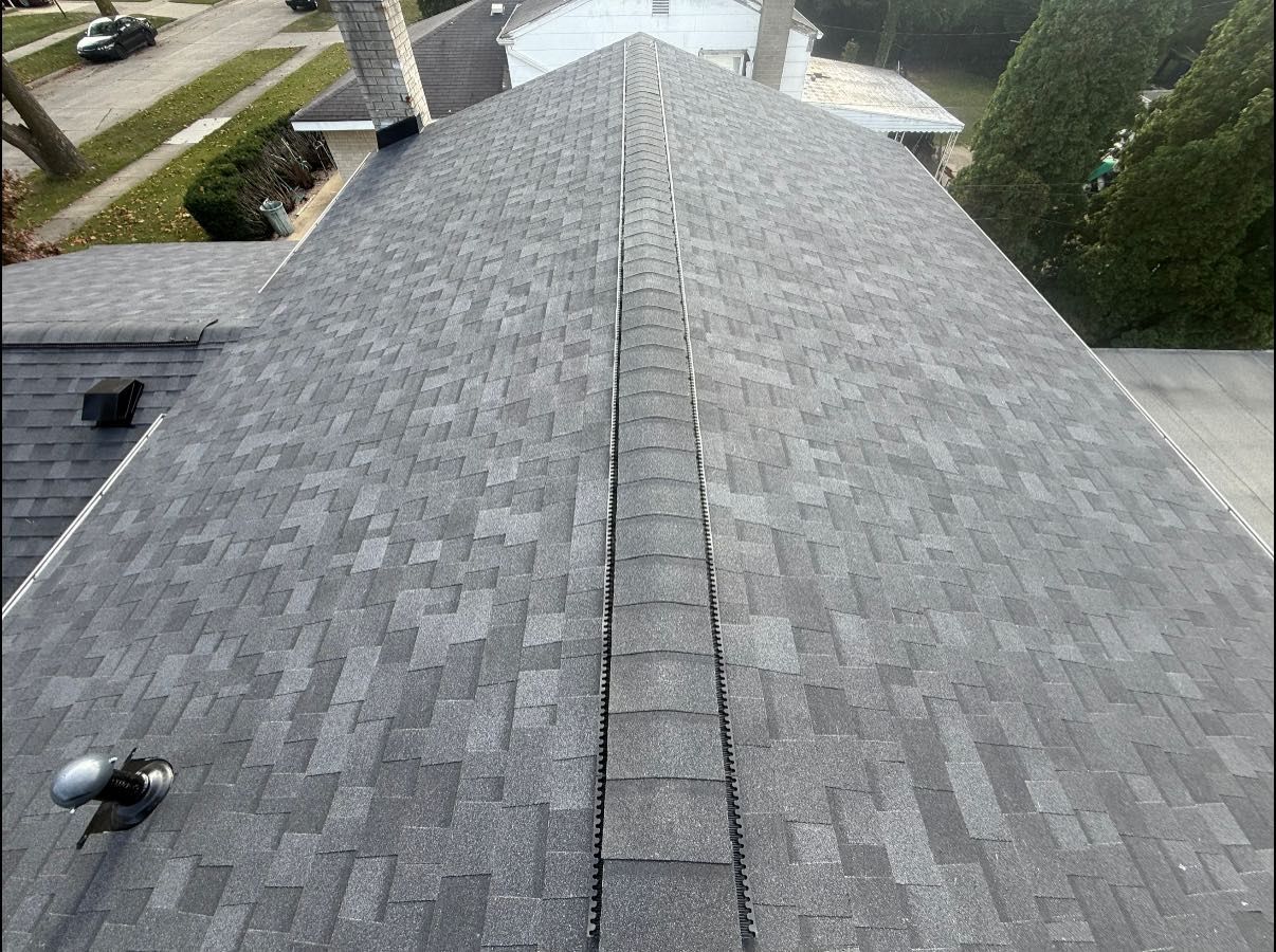 Gray asphalt shingle roof, with a central ridge. Includes a chimney and vents, viewed from above.