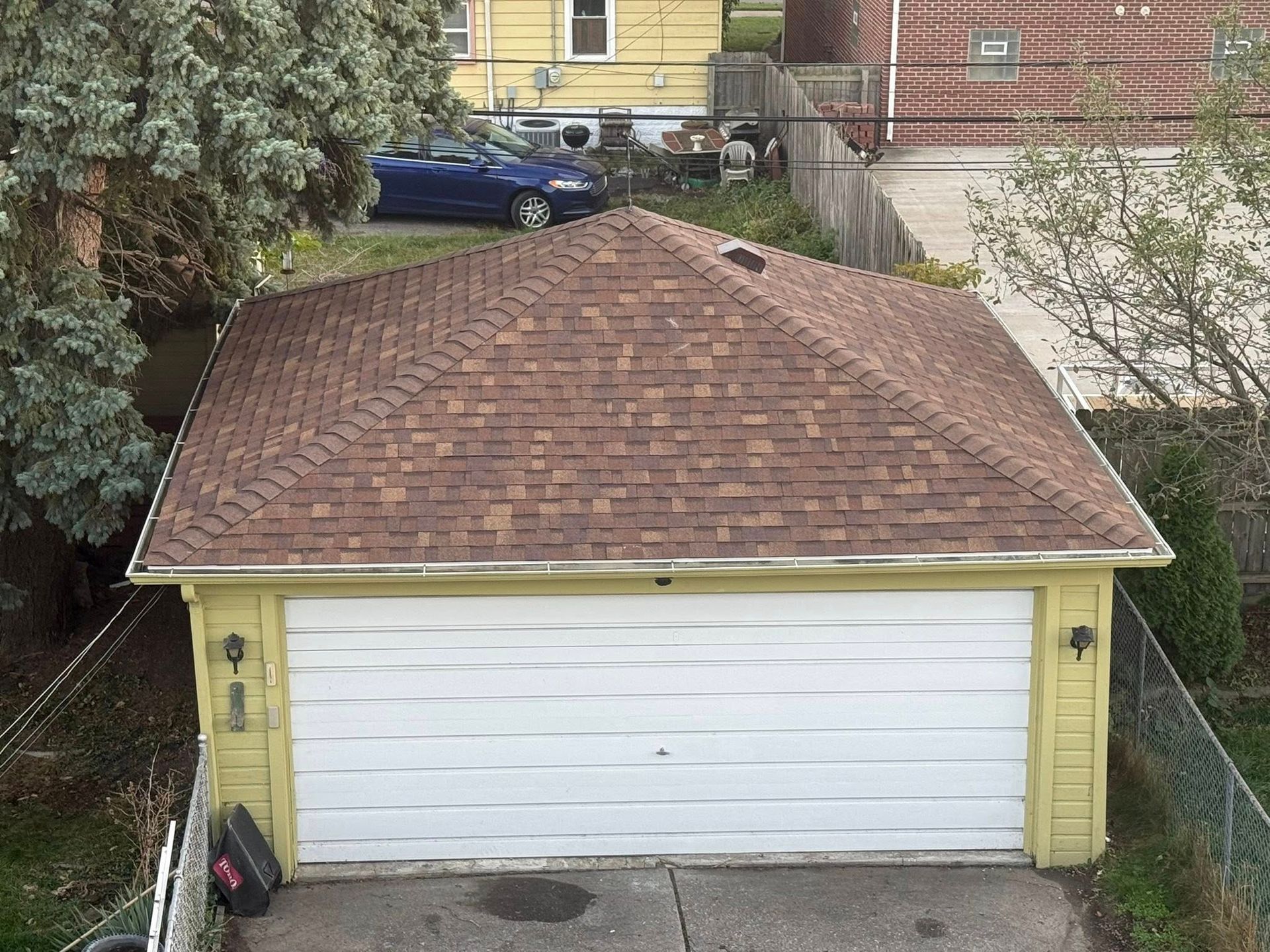 Yellow garage with brown roof; blue car parked in the background.