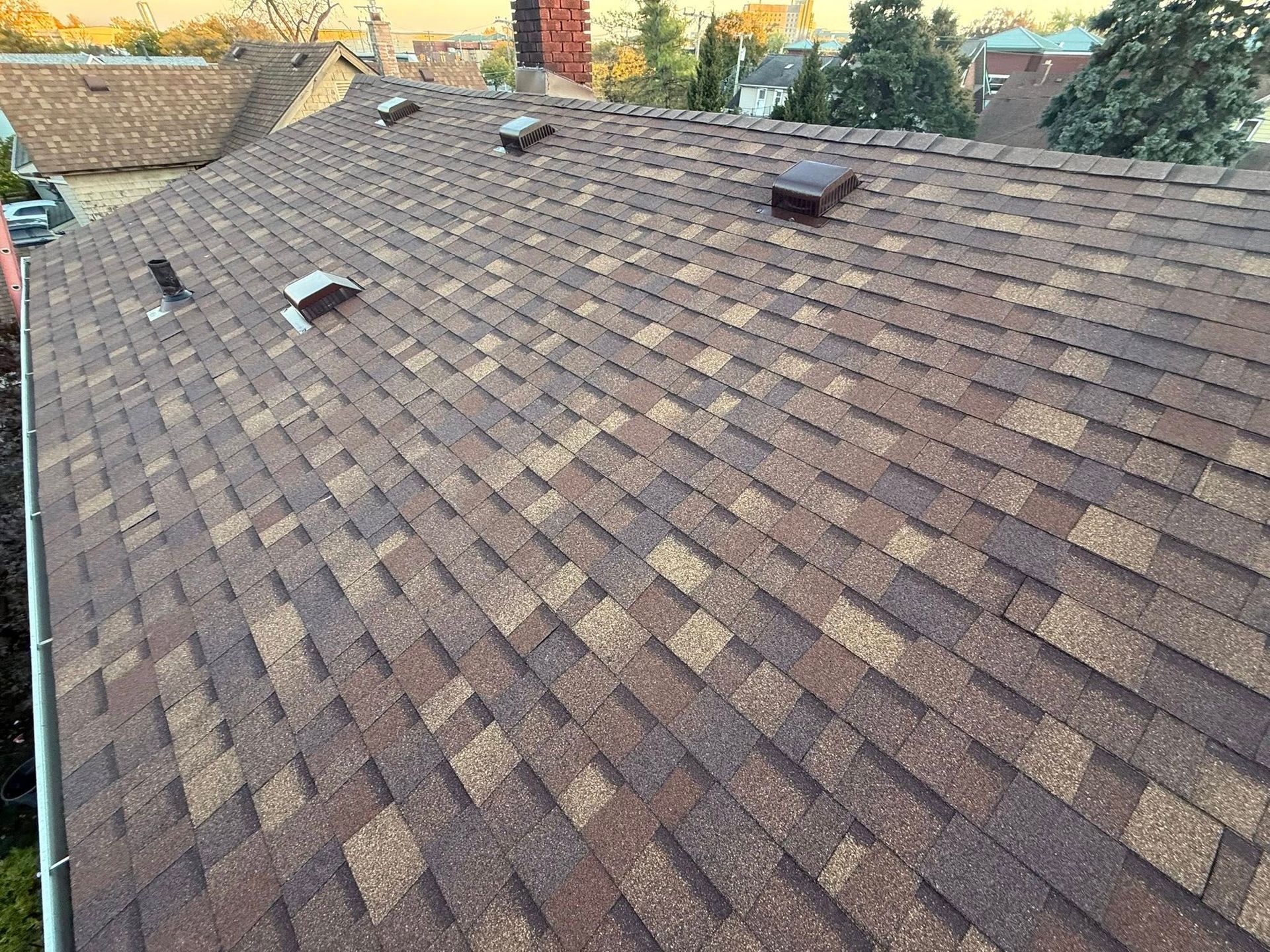 Brown and tan asphalt shingle roof with several vents.