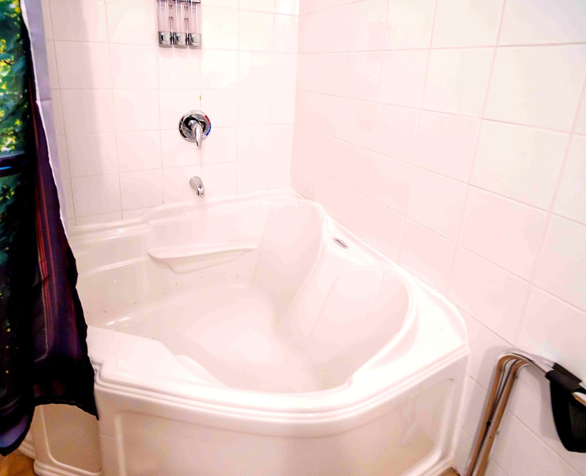 Baignoire blanche remplie d'eau ; salle de bains avec murs carrelés blancs et robinet chromé.