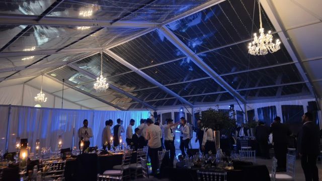 Sous une tente événementielle éclairée par un lustre, des personnes étaient rassemblées autour de tables.