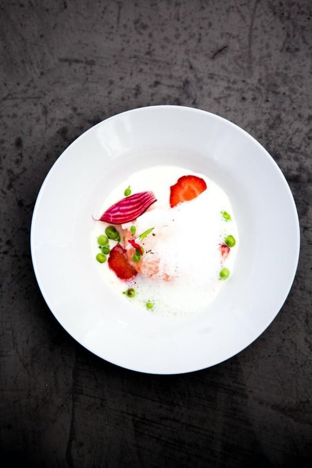 Bol blanc de soupe crémeuse aux fraises, aux petits pois et à la betterave rouge.