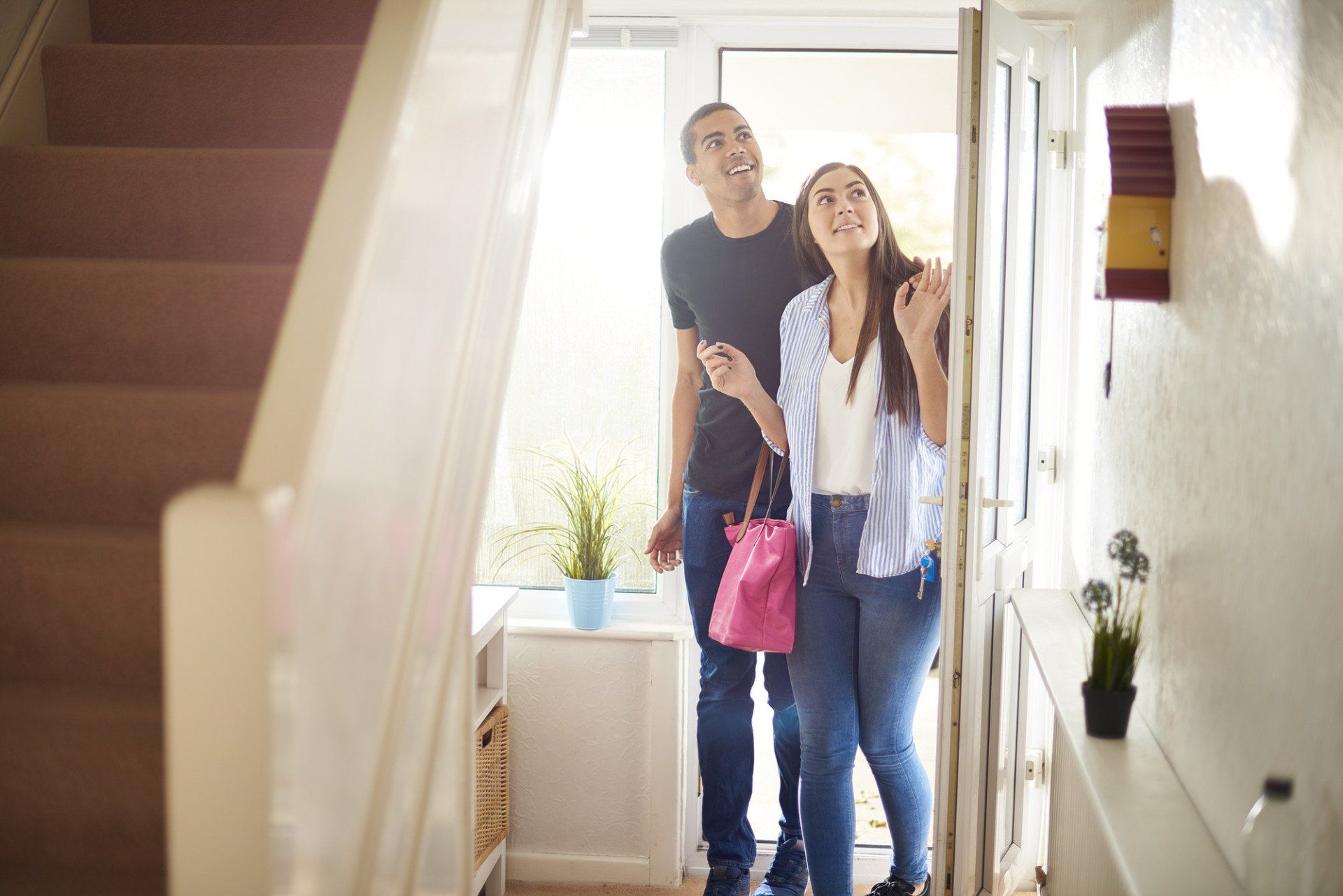 a young couple view a property . They are standing in the hallway of house and looking around with excited expressions.