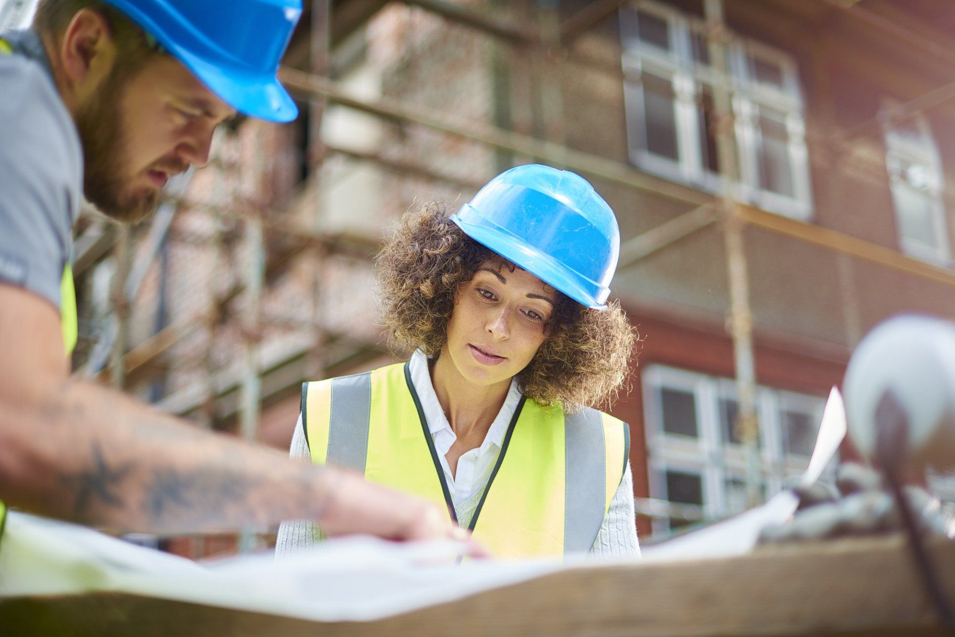 a female architect stands on a building site housing development and instructs a co -worker.