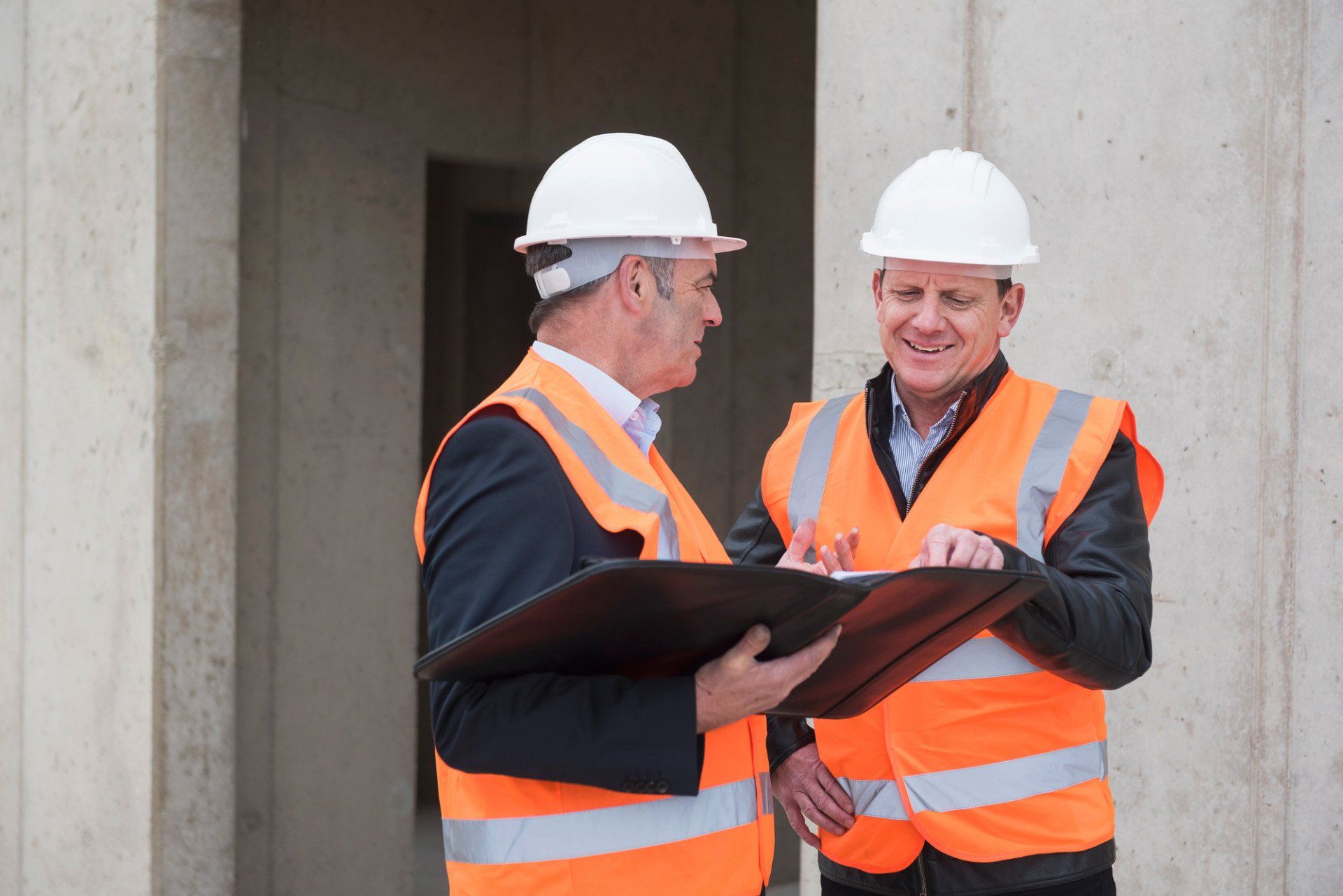 Two men wearing safety vests talking on construction site