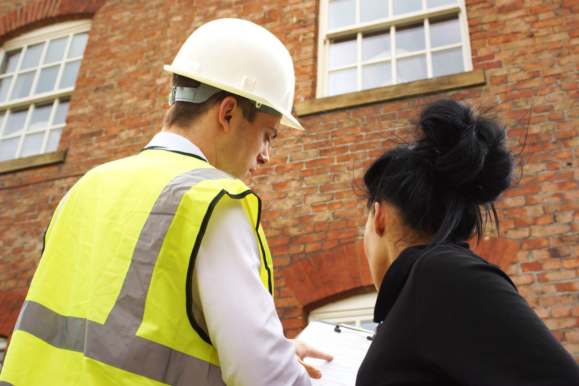 A builder, contractor or surveyor discussing a property quotation or contract with a homeowner. Part of a series with these models.