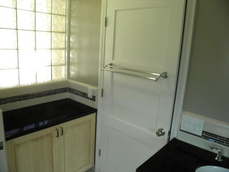 A bathroom with white cabinets and a black counter top