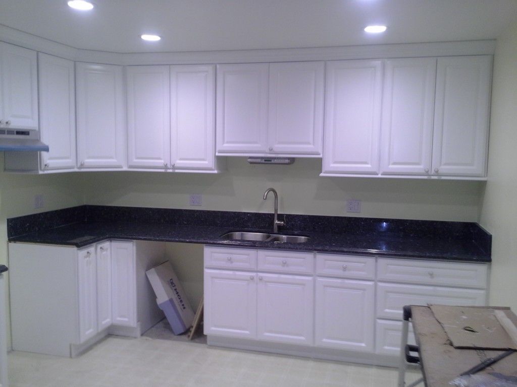 A kitchen with white cabinets and black counter tops