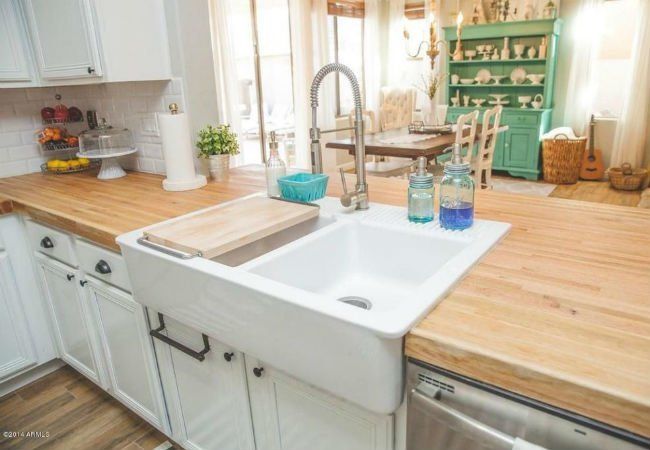 A kitchen with a white sink and a wooden counter top.