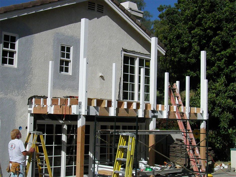 A man standing on a ladder in front of a house