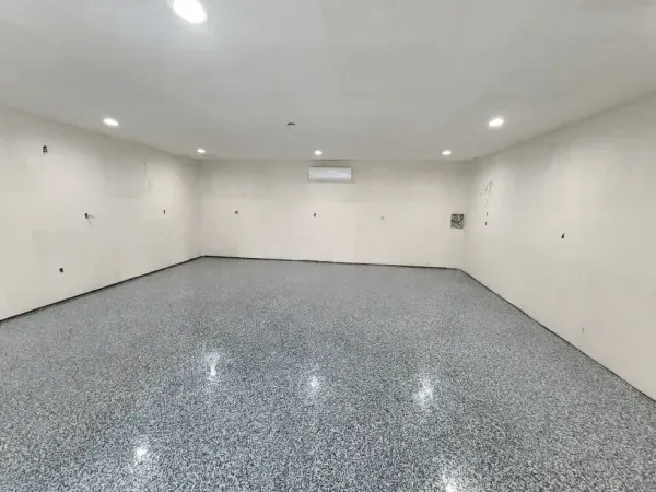 Empty room with gray speckled flooring, white walls, and recessed lighting.