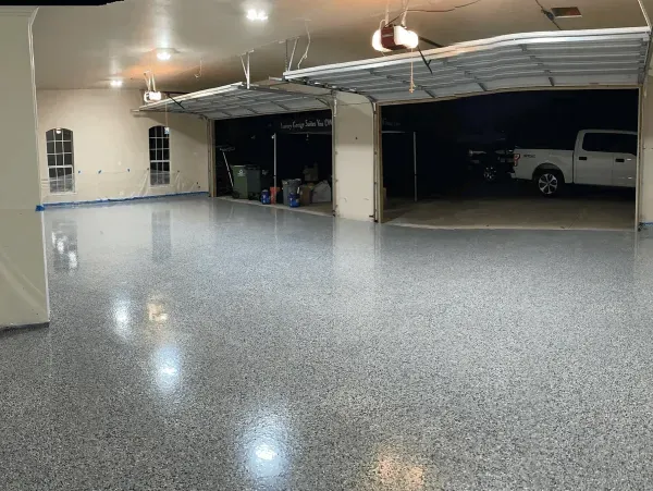 Garage with glossy gray speckled epoxy floor, open garage doors, and white pickup truck.