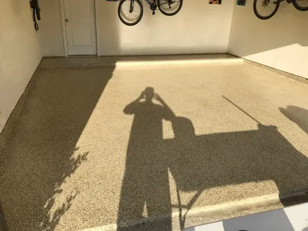 Shadow of person taking photo in garage with speckled floor and bikes.