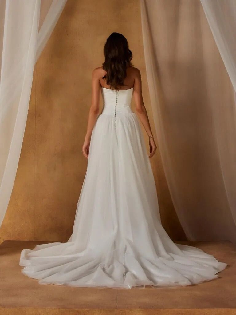Our Nordic wedding dress exists in the space between modern and whimsical. Blending the two styles seamlessly for a look that feels both romantic and fashionable in the most effortless way.
The clean, velvet satin bodice begins at a contemporary scoop neckline. With the option to be worn strapless or with spaghetti straps for added support. Curved seamlines create shape throughout the bodice, ending at the sharp Basque waist that cinches the figure.